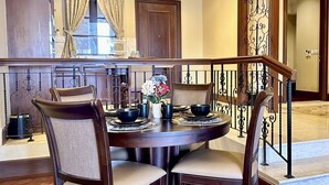 A dining area with a round table, four chairs, and a decorative centerpiece. - Casa Del Rio Residence (Malacca City)