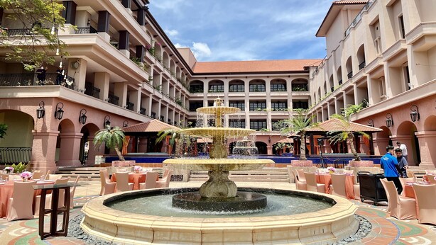 A courtyard with a central fountain, outdoor seating, and a multi-story building with balconies. - Casa Del Rio Residence (Malacca City)