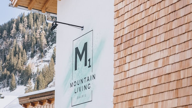 A building with a sign reading "M1 Mountain Living" and a wooden exterior. - M1 - Apartment with garden 2 (Rauris)