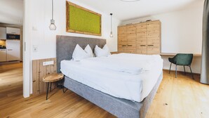 A bedroom with a large bed, a wooden wardrobe, a desk, and a chair. - M1 - Apartment with garden 2 (Rauris)