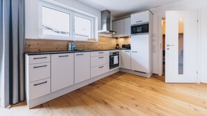 A modern kitchen with white cabinets, a wooden countertop, and a large window. - M1 - Apartment with garden 2 (Rauris)