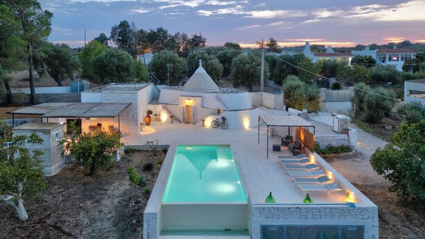 Una vila moderna amb piscina, zona de seients a l'exterior i jardí.