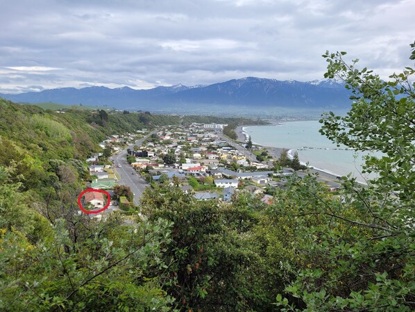 Un pueblo costero con una carretera que lleva a una playa, rodeado de montañas y vegetación.