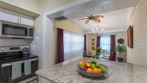 A kitchen with a microwave, stove, and a bowl of fruit on the counter. - Tropical Vibes! Spacious 3BD/2BA, BBQ, Parking & more -10 min to Best Locations (West Palm Beach)