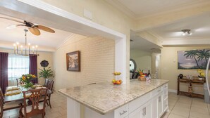A spacious kitchen with a large island, white cabinetry, and a dining area with a wooden table and chairs. - Tropical Vibes! Spacious 3BD/2BA, BBQ, Parking & more -10 min to Best Locations (West Palm Beach)