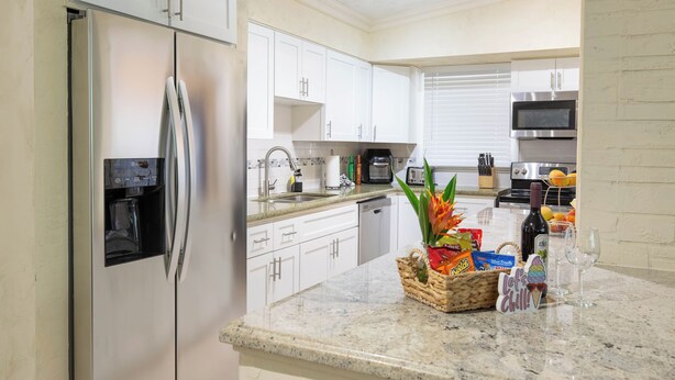 A modern kitchen with white cabinets, stainless steel appliances, and a granite countertop. - Tropical Vibes! Spacious 3BD/2BA, BBQ, Parking & more -10 min to Best Locations (West Palm Beach)