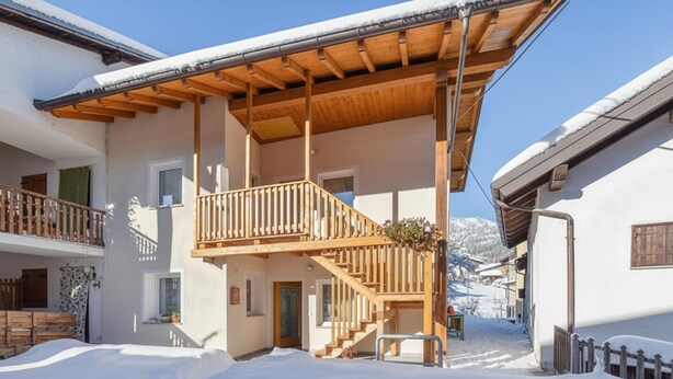 A multi-story building with a wooden balcony and a staircase leading to the upper floor. - 2 bedroom gorgeous home in Lamon (Lamon)