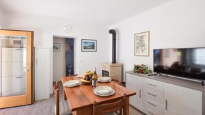A compact living space with a wooden dining table, a built-in TV, and a kitchenette. - 2 bedroom gorgeous home in Lamon (Lamon)