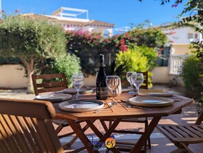 Mesa de madera al aire libre con copas de vino, platos y una botella.