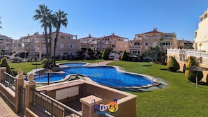 Un hotel con piscina, palmeras y un césped bien cuidado.