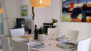 Un comedor con una mesa preparada para cuatro, una botella de vino y una planta en maceta.