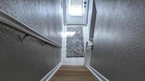 Una escalera con peldaños de madera y un rellano alfombrado.