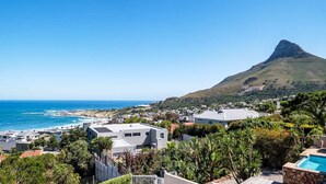 A coastal town with modern houses, a prominent mountain, and a clear blue sky. - Seaside Escape Apartment Sea La View (Cape Town)