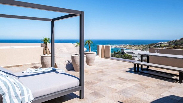 A balcony with a bed, potted plants, and a view of the ocean. - Seaside Escape Apartment Sea La View (Cape Town)