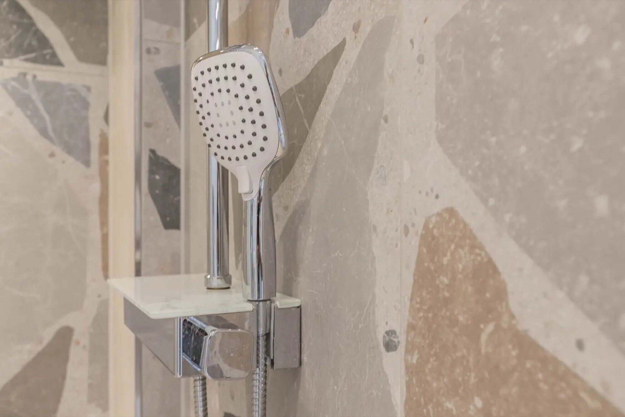 Un pommeau de douche au design perforé, fixé sur un support chromé.