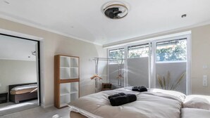 Un dormitorio con cama, armario, espejo y ventana.