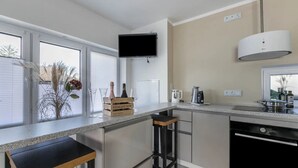 Una cocina moderna con barra, televisor montado sobre la encimera y ventana con vistas.