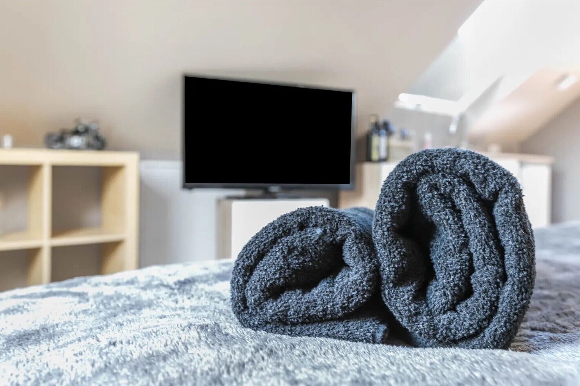 A bedroom with a bed, a TV, and a shelf with items.