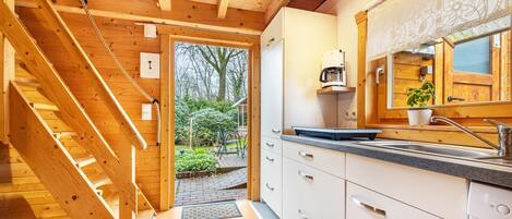 Een houten interieur met een keukenhoek, inclusief een gootsteen, kastjes en een trap naar buiten.