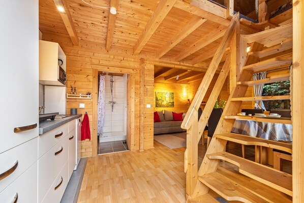 Un intérieur en bois comprenant une cuisine, un escalier et un espace de vie.