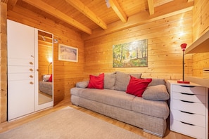 L’intérieur d’un chalet en bois, avec un canapé, un meuble et un tableau accroché au mur.