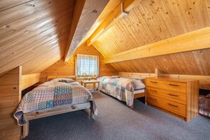 Une chambre dans une cabane en bois, avec deux lits, un bureau et une commode.