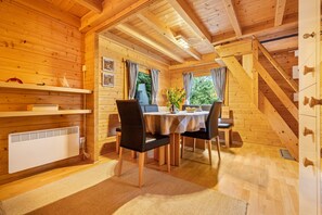 L’intérieur d’une cabane en bois, avec un coin repas, un radiateur et un escalier.