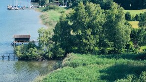 Vista para o lago com barcos, um cais e uma área arborizada.