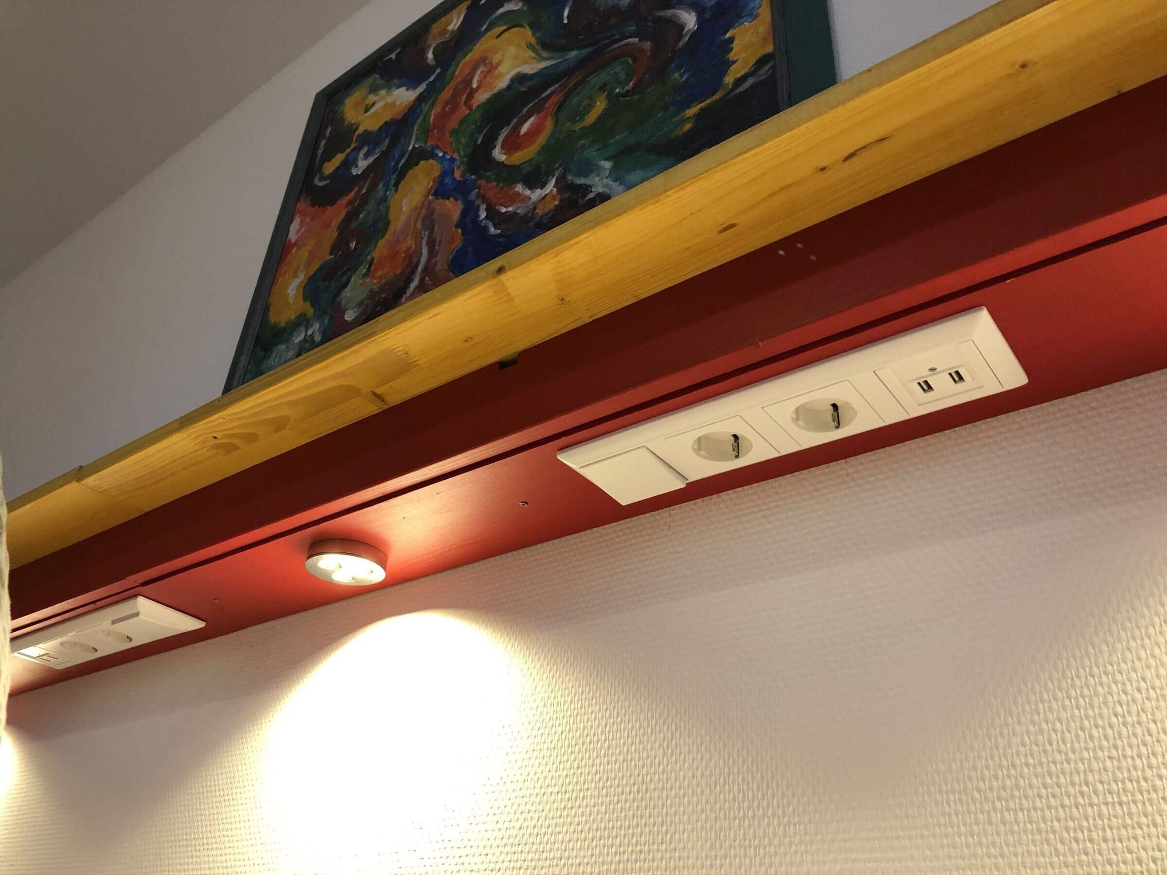Un techo con iluminación empotrada, una viga de madera y un cuadro de colores.