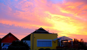 Un immeuble résidentiel avec un garage, un porche couvert et, au fond, une grange rouge.