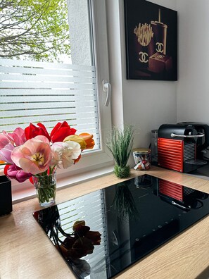 A kitchen counter with a vase of flowers, a small plant, and a coffee maker.