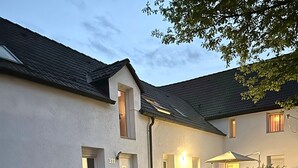 Un bâtiment à deux étages, à l’extérieur blanc, avec une porte bien visible portant l’inscription « 311 », et un petit patio aménagé avec du mobilier d’extérieur.