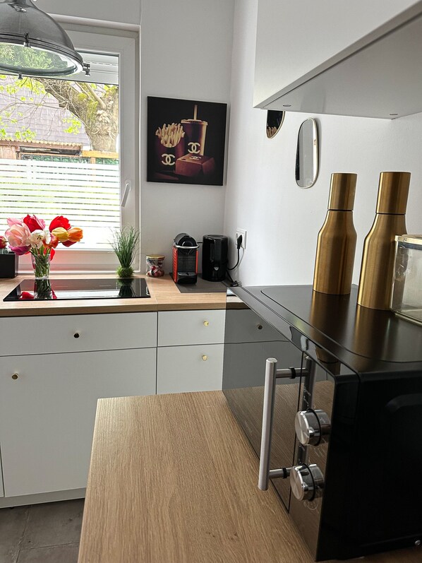 A modern kitchen with a window, a coffee machine, and a vase with flowers.
