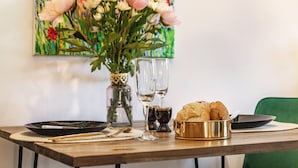 Une table à manger avec un vase de fleurs, deux verres à vin, un panier de pain et des couverts.