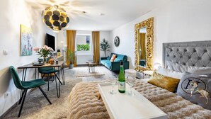 Un salon moderne comprenant un coin repas, un canapé, un grand miroir et un luminaire décoratif au plafond.