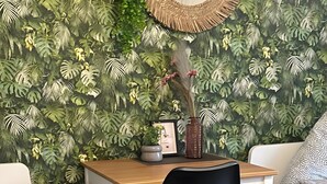 A room with a desk, a chair, a sofa, and a wall with a leafy pattern. - Apartment 'Apartement Kingsize' with Shared Terrace and Wi-Fi (Duisburg)