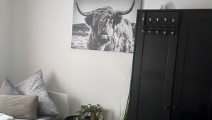 A modern room with a wooden dining table, a sofa with patterned cushions, a black cabinet, and a wall-mounted picture of a bull. - Apartment 'Apartement Kingsize' with Shared Terrace and Wi-Fi (Duisburg)