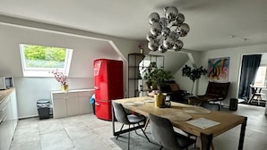 Ett modernt kök med matplats, ett rött kylskåp och ett stort fönster.