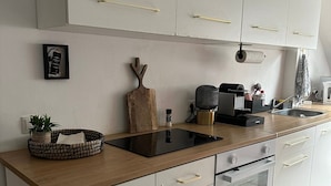 Ett modernt kök med vita skåp, en bänkskiva i trä och en inbyggd ugn.