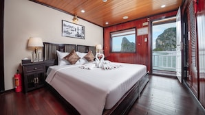 A hotel room with a large bed, wooden ceiling, and a balcony with a view of cliffs. - Ruby Cruise (Tuan Chau)
