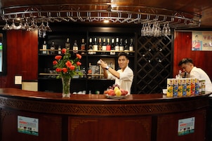 Angolo bar con bancone, bottiglie di vino e esposizione di frutta.