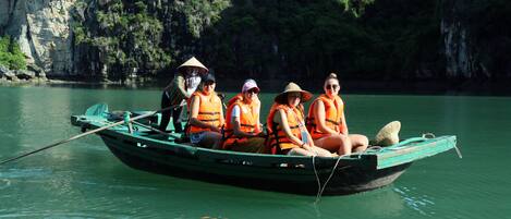 A group of people in a boat on a calm river with rocky cliffs in the background.