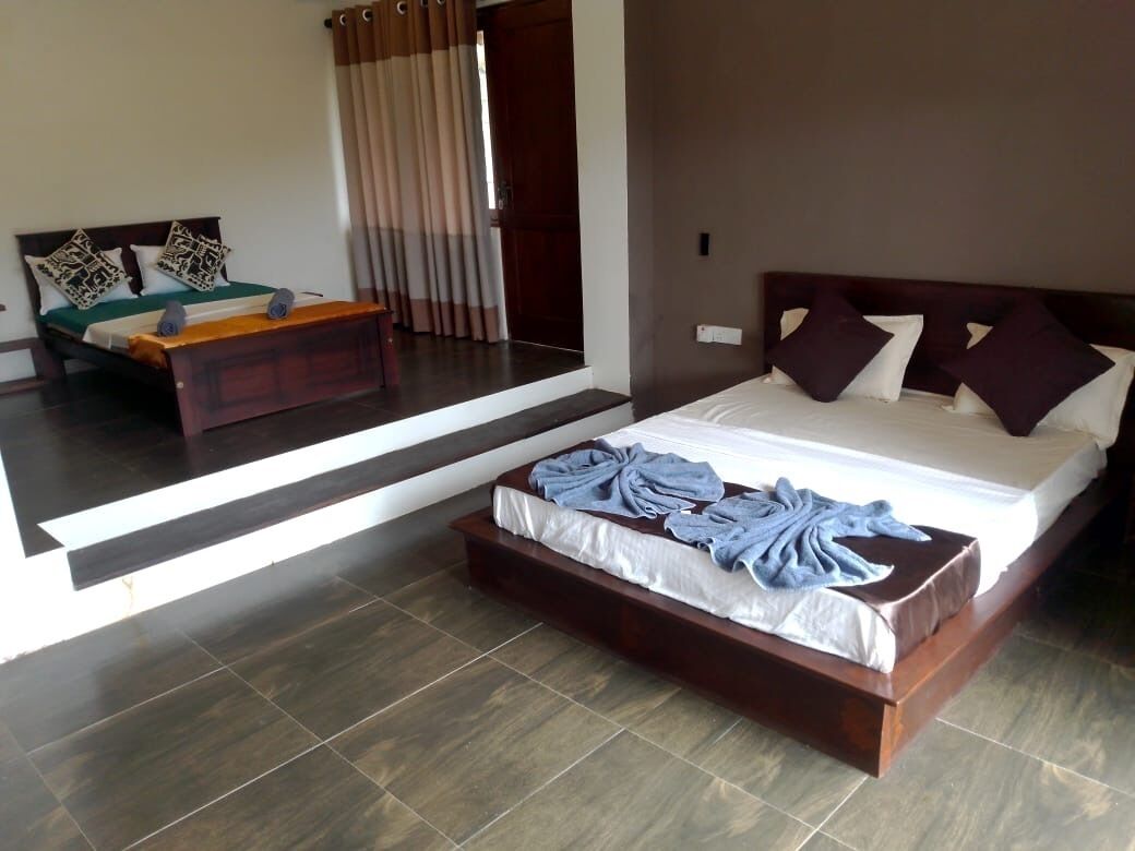 Habitación de hotel moderna con una cama grande, un banco de madera y vistas al exterior a través de una puerta de vidrio.