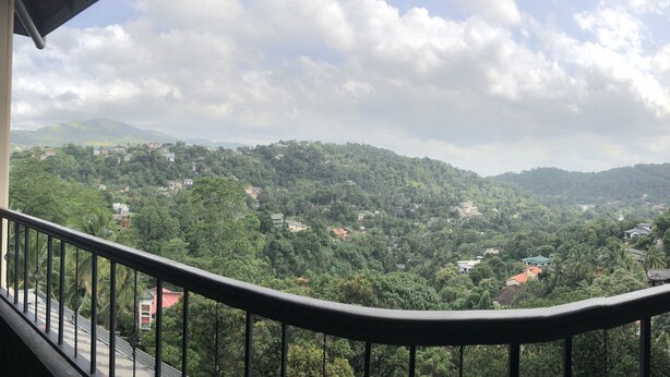 A balcony with a view of a mountainous landscape and scattered houses. - Riverdale Ridge Apartment II (Kandy)
