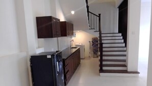 A kitchen with a refrigerator, cabinets, and a staircase leading to another level. - Riverdale Ridge Apartment II (Kandy)