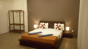 A neatly made bed with a wooden headboard, two bedside lamps, and a wooden nightstand. - Riverdale Ridge Apartment II (Kandy)