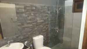 A bathroom with a white sink, toilet, and glass shower enclosure. - Riverdale Ridge Apartment II (Kandy)
