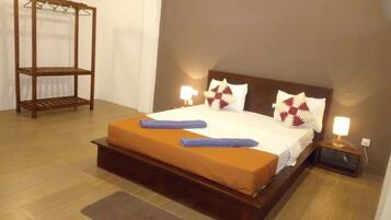 A neatly made bed with a wooden headboard, two bedside lamps, and a wooden shelf unit.
