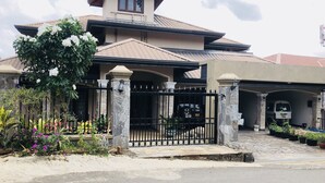 A two-story house with a gated entrance, a covered driveway, and a vehicle parked inside. - Riverdale Ridge Apartment II (Kandy)