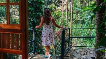 A woman in a polka dot dress walking on a stone pathway surrounded by lush greenery.